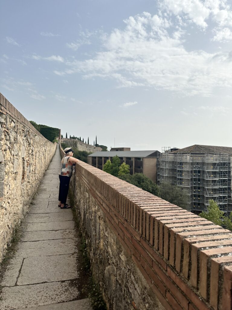 woman looks over the city walls in girona spain on a day trip from barcelona