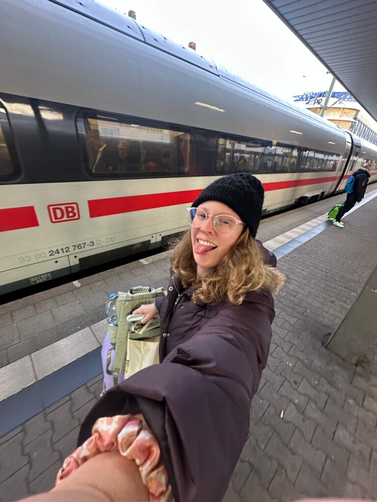 girl sticks her tounge out with luggage taking train in germany standing on platform
