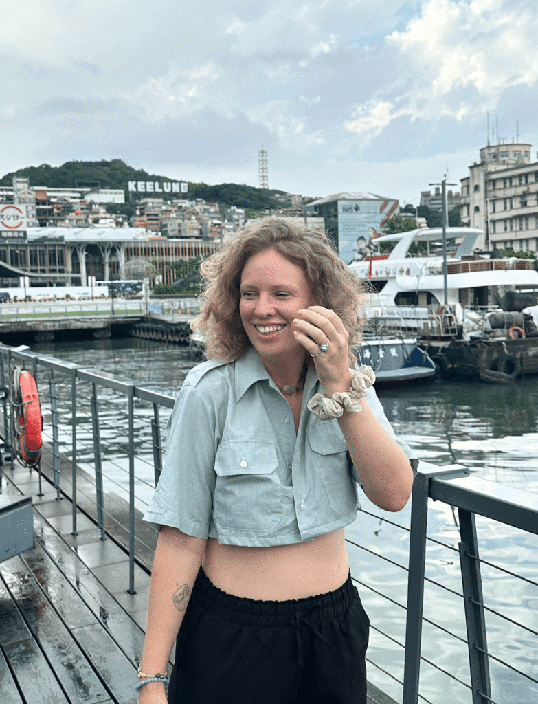 girl smiling with photos of keeling sign in taiwan behind her