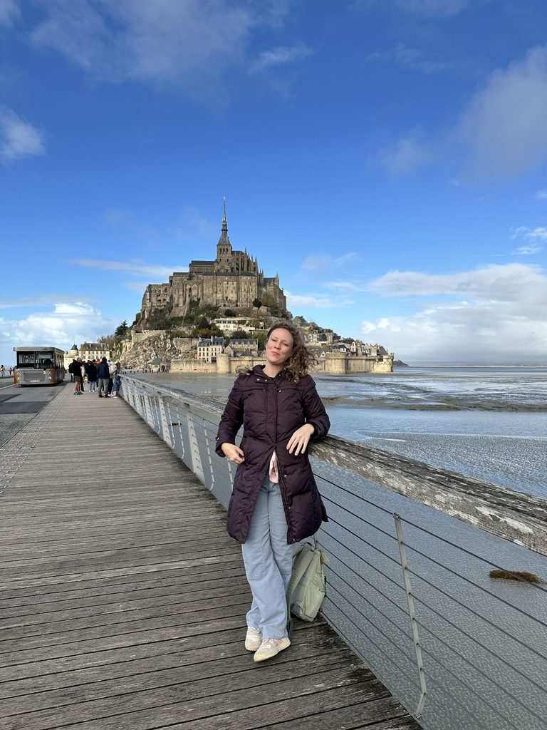 tourist stands in front of Mont Saint-Michel on a sunny day