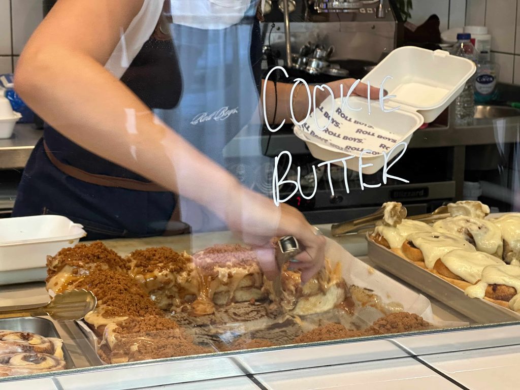 Girl picking up a cookie butter cinnamon roll at Roll Boys in London 