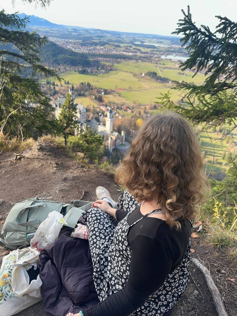 traveler has a picnic with view above Neuschwanstein Castle in Germany on a day trip from Munich in November