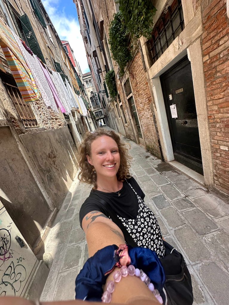 taking a selfie in an alleyway in venice italy with laundry hang drying from a window
