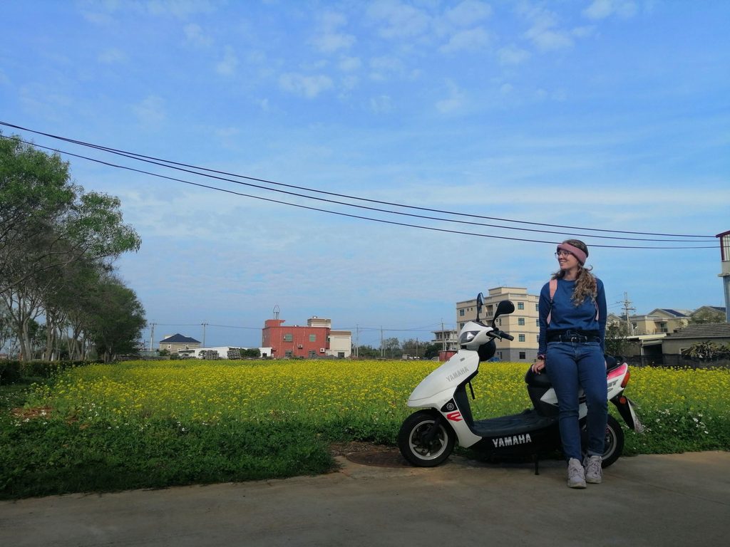 girl leans on scooter in field of flowers on kinmen in taiwan