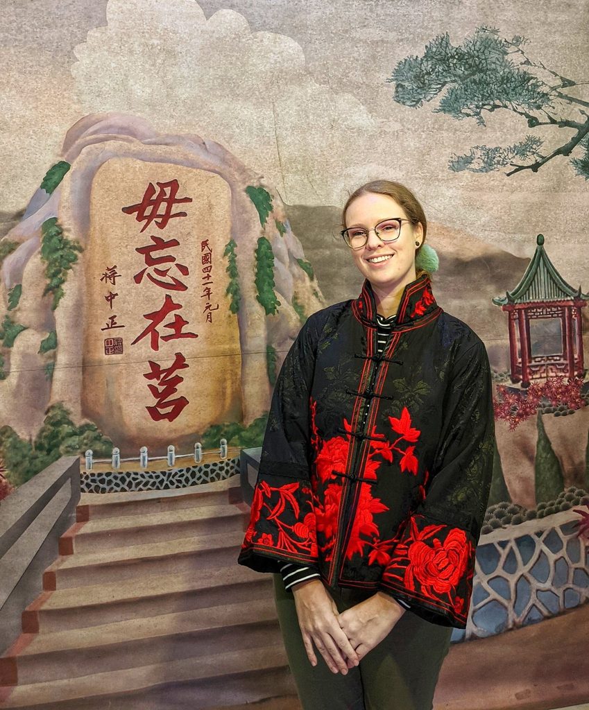 woman poses in traditional jacket with backdrop unique things to do in kinmen island